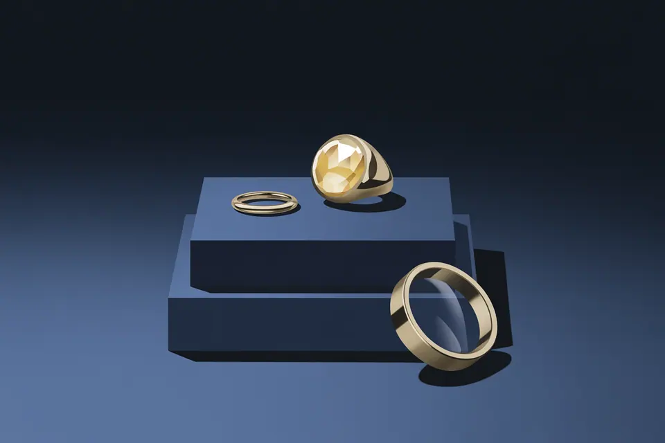 Gold-tone rings and plain bands arranged on and beside navy display blocks.