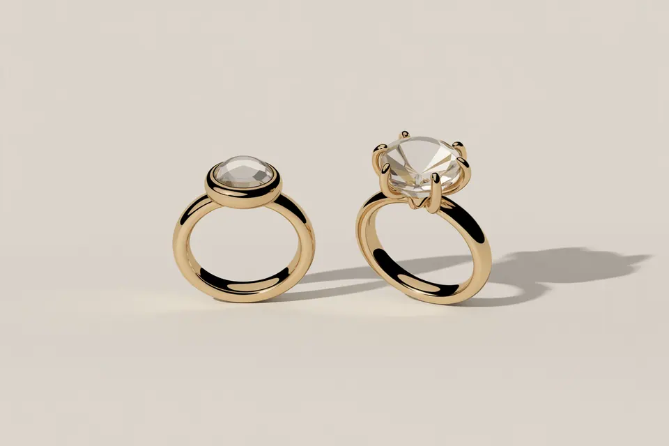 Gold-tone rings with a low metal-rimmed stone and a raised stone held by prongs.